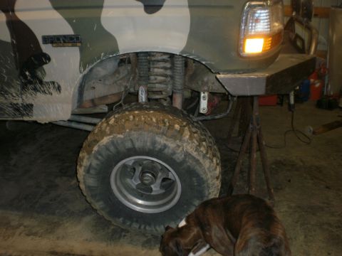 1995 Ford Bronco - A muddy Ford Bronco with camouflage paint is shown from the front quarter, resting on a jack stand.