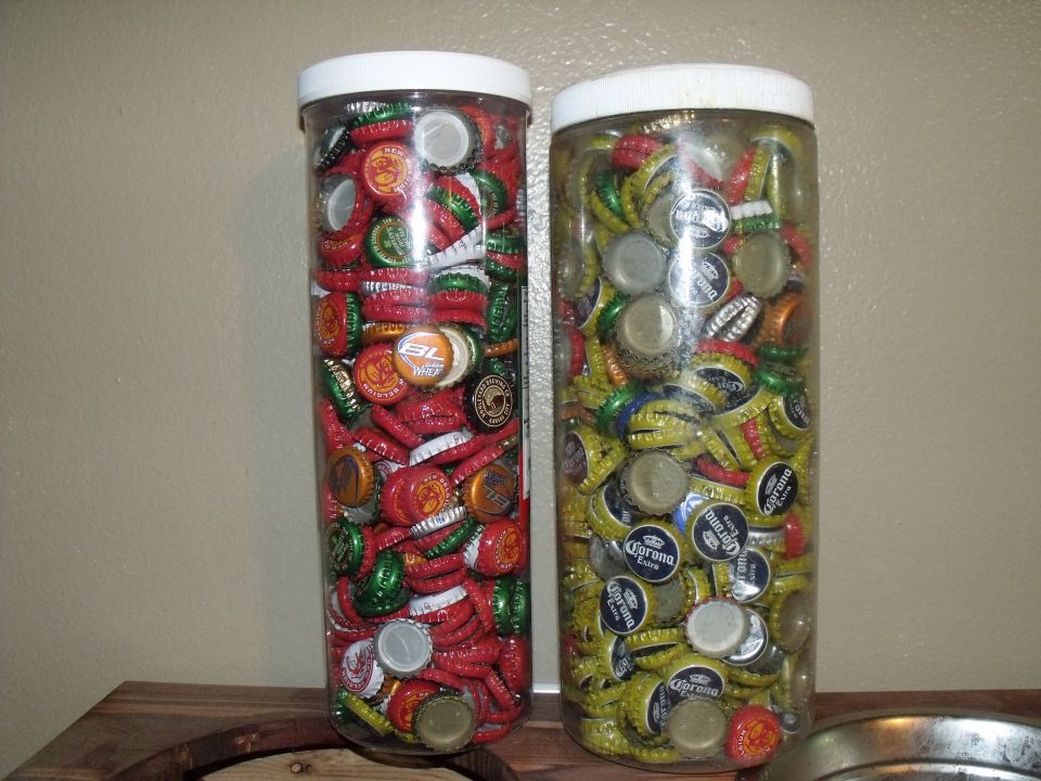 Two clear plastic jars filled with beer bottle caps, one red and green, the other yellow and blue