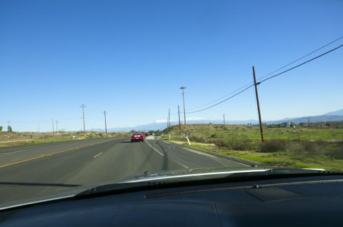 2006 Cadillac STS - Driving on a highway with a red car ahead and mountains in the distance under a clear blue sky.