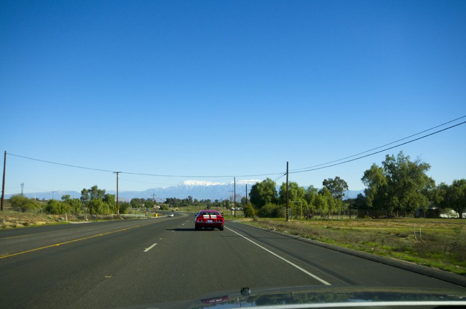 Red sports car driving on a highway with mountains in the background