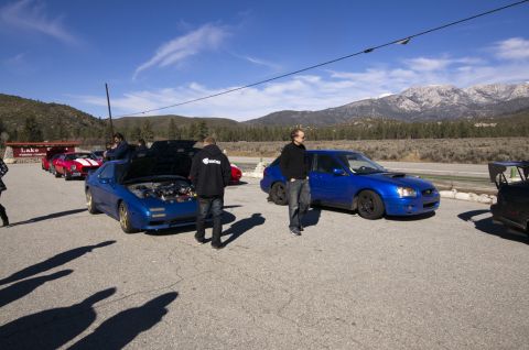 2006 Cadillac STS - Two blue cars are parked on asphalt, with mountains visible in the distance.