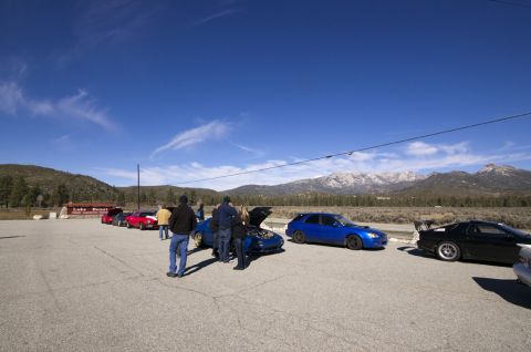 2006 Cadillac STS - Cars and people are gathered in a parking lot with a mountainous backdrop under a clear blue sky.