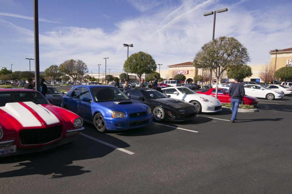 Red striped Camaro, blue Subaru WRX and white 370Z parked at a shopping center car meet