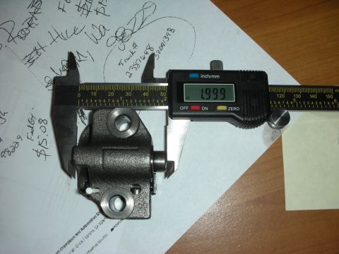 1992 Ford Crown Victoria - A digital caliper measures a metal engine part, with handwritten notes and a sticky note in the background.