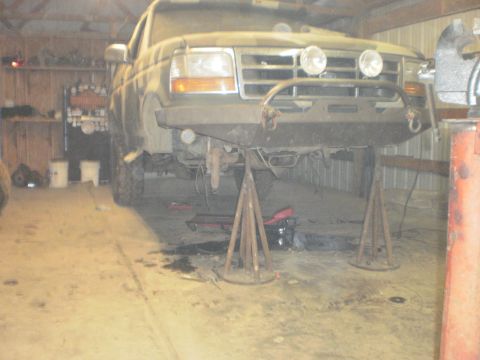 1995 Ford Bronco - This 1995 Ford Bronco is elevated on jack stands, suggesting it is undergoing maintenance or modification in a garage setting.