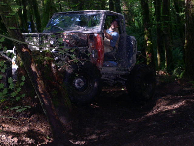guy driving beat-up off-road vehicle in woods