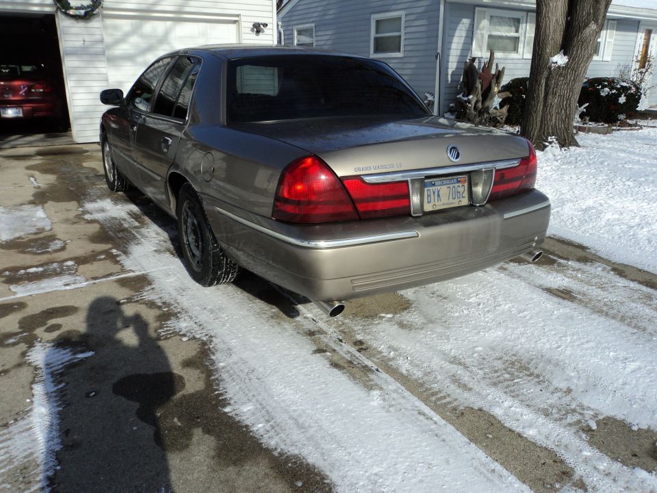 Rear view of tan Mercury Grand Marquis LS sedan on snowy driveway with Michigan plate
