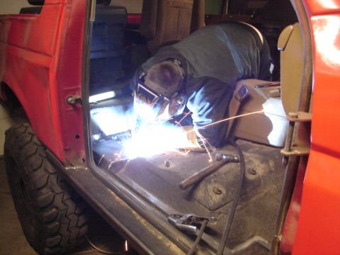 1989 Ford Bronco - Welder works on the interior floor of a red 1989 Ford Bronco.