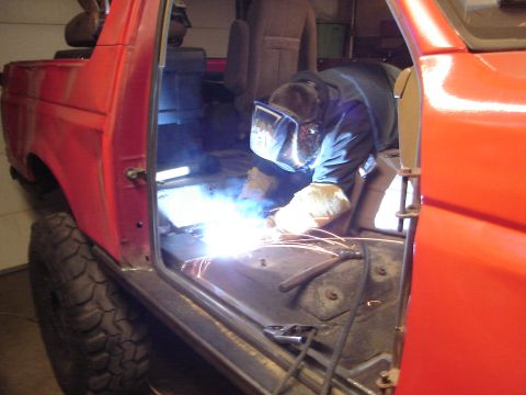 1989 Ford Bronco - Welding repairs being done on the interior floor of a red 1989 Ford Bronco.