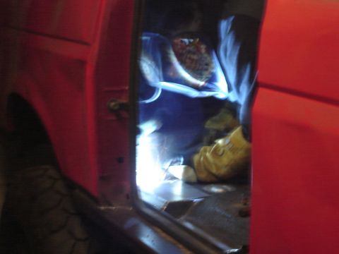 1989 Ford Bronco - A person is welding inside a red vehicle, with bright sparks illuminating the interior.