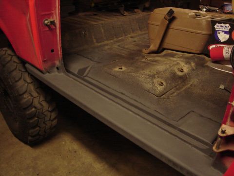 1989 Ford Bronco - Interior view of a red vehicle with a gray rocker panel and a tan storage box visible.