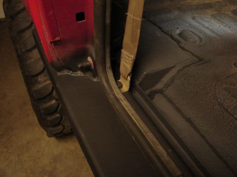1989 Ford Bronco - Close-up view of a vehicle's interior, highlighting the seatbelt, tire, and floor panel.