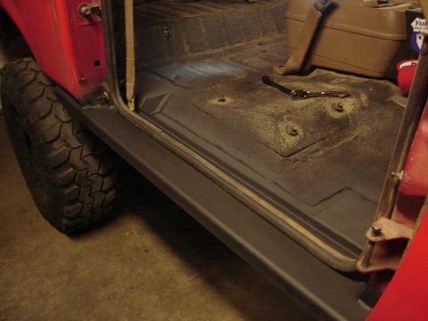 1989 Ford Bronco - Close-up of a vehicle's interior, focusing on the floor and door area, with a tire visible outside.