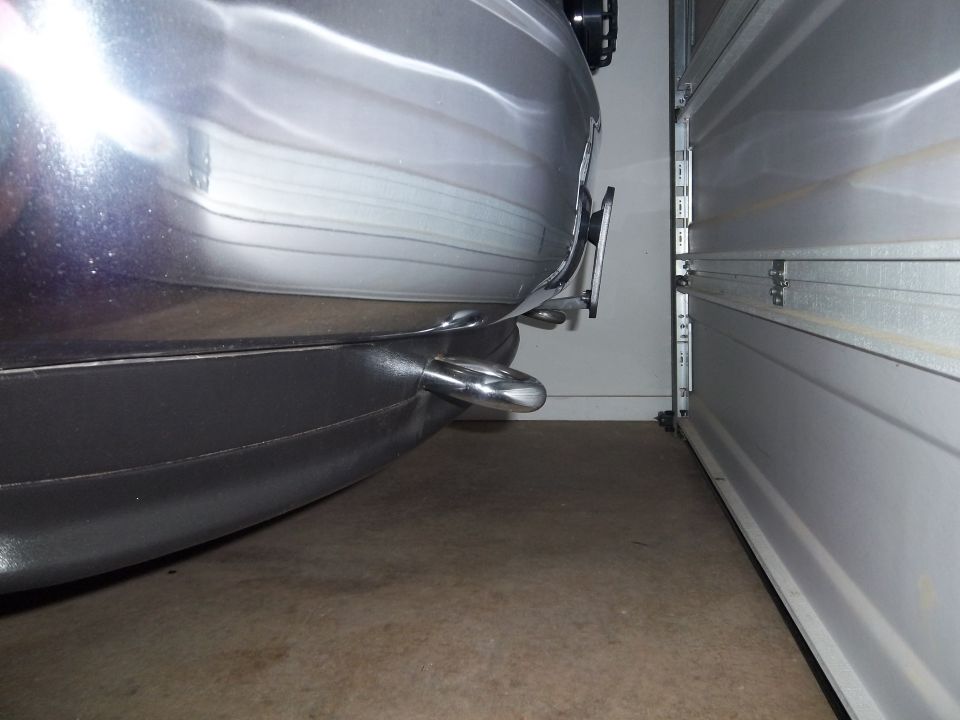 rear bumper and tow hook of a vehicle parked next to an open garage door