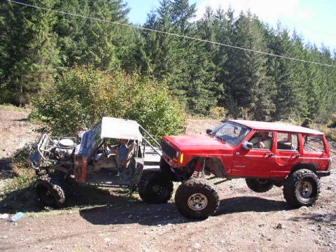 1979 Ford Bronco - A custom buggy tows a red SUV on a dirt path, with a dense forest lining the background.
