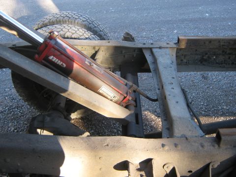 1972 Ford F-250 - Close-up of a hydraulic cylinder and the frame of a truck, with dual rear tires in the background.