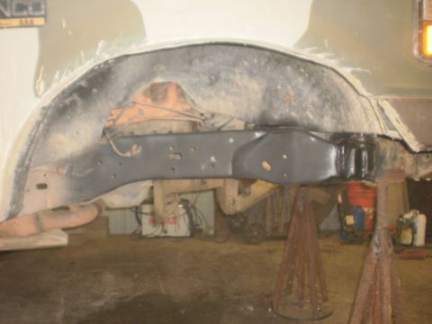 1995 Ford Bronco - The underside of a vehicle, showing the frame and suspension, is visible in this garage setting.