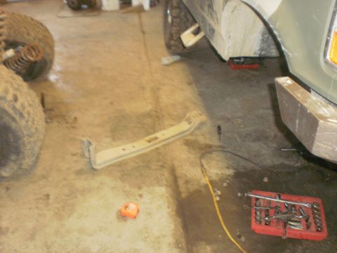 1995 Ford Bronco - A detached vehicle frame component lies on the garage floor next to tires and a toolbox.