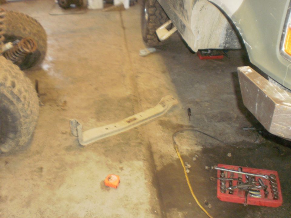Vehicle frame part on floor with tires and tools nearby