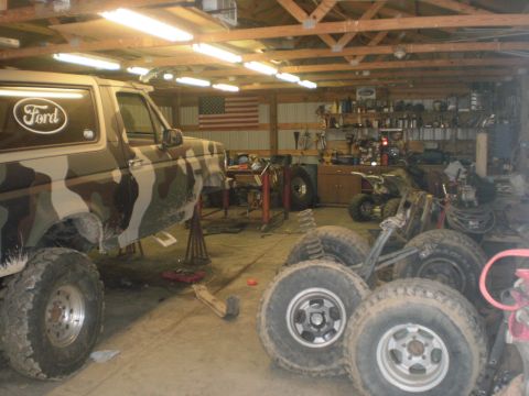 1995 Ford Bronco - Camouflaged 1995 Ford Bronco undergoing work in a garage, surrounded by tools and spare tires.