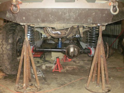 1995 Ford Bronco - The underside of a vehicle is elevated on jack stands, revealing its suspension components and differential for maintenance or modification.