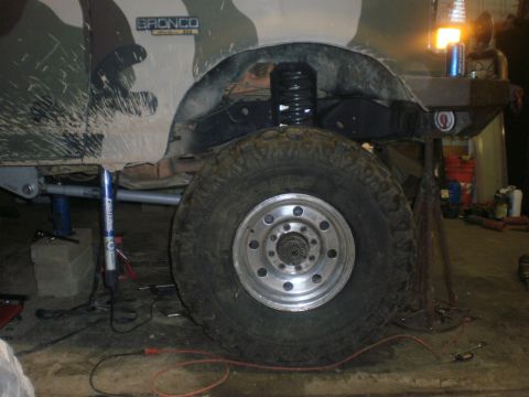 1995 Ford Bronco - A camouflaged Ford Bronco is shown from the side, lifted and supported by a jack in a workshop.
