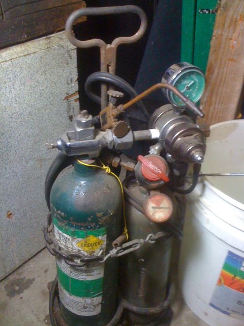 1968 Ford Mustang - Two industrial gas tanks, likely oxygen and acetylene, are chained together with pressure gauges and hoses attached.