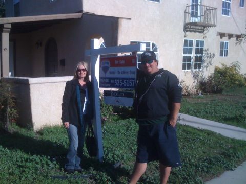 1968 Ford Mustang - A real estate agent and client pose with a sold sign outside a house.