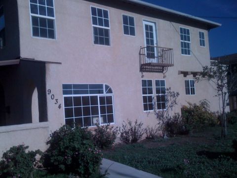 1968 Ford Mustang - The building at 9034 has a tan stucco exterior with several windows and a small balcony.