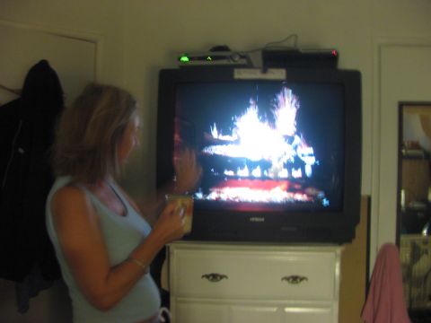 1968 Ford Mustang - A woman watches a television displaying a fireplace scene while holding a mug.