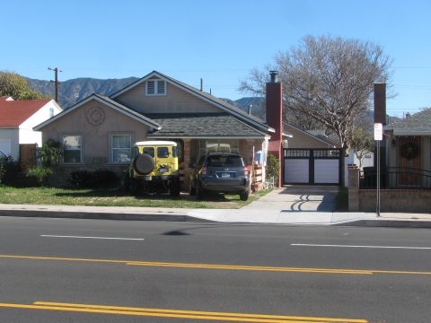 1968 Ford Mustang - Two vehicles are parked in the driveway of a suburban house on a sunny day.