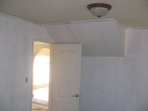 1968 Ford Mustang - A view into a room with a white door, leading to a brightly lit area with an archway.
