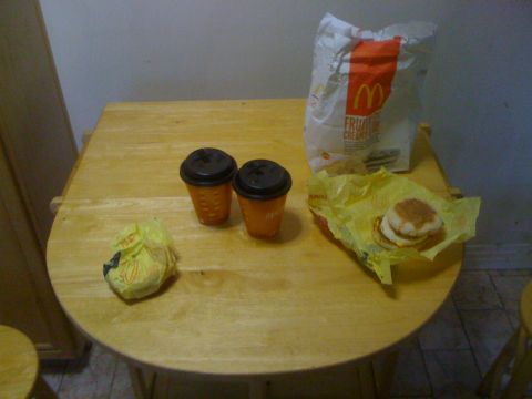 1968 Ford Mustang - A meal from McDonald's sits on a wooden table, including a bag, coffee cups, and a sandwich.