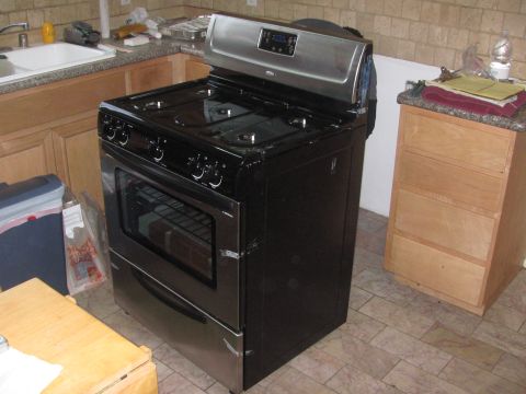 1968 Ford Mustang - A black gas range with stainless steel accents is shown in a kitchen setting next to a wooden cabinet.