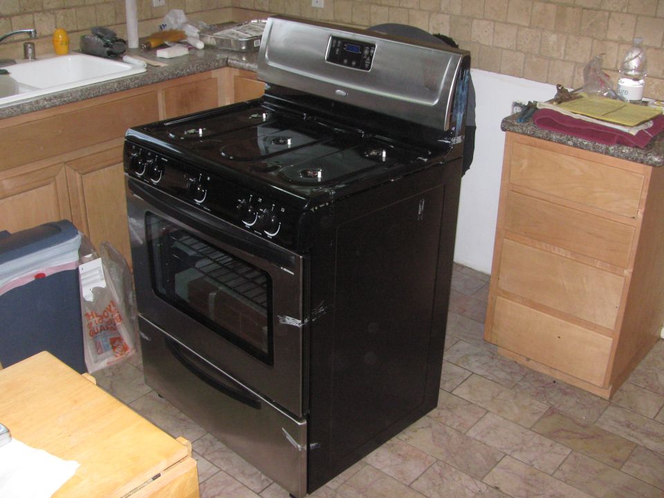 Black gas range with stainless steel control panel and oven door in a kitchen