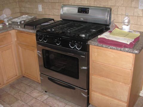 1968 Ford Mustang - A stainless steel gas range is shown in a kitchen setting with tiled backsplash and floor.