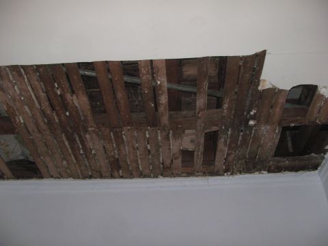 1968 Ford Mustang - A section of ceiling has collapsed, revealing the underlying wooden structure and plumbing.