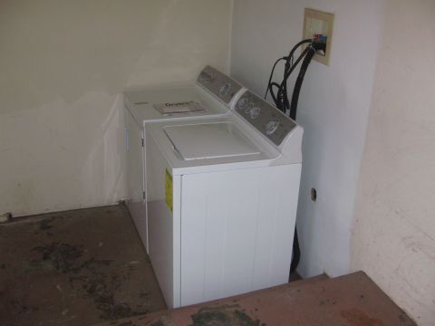 1968 Ford Mustang - A white washing machine and dryer set is shown in a room with beige walls and a concrete floor.