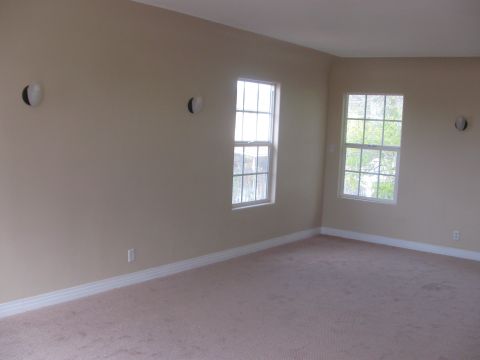 1968 Ford Mustang - A view of an empty room with beige walls, carpet, and two windows showing greenery outside.