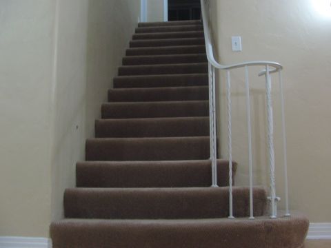 1968 Ford Mustang - A carpeted staircase ascends with a white railing along the side.