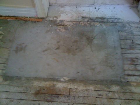 1968 Ford Mustang - A patch of concrete is laid over a section of a wooden floor, showing signs of wear and tear.