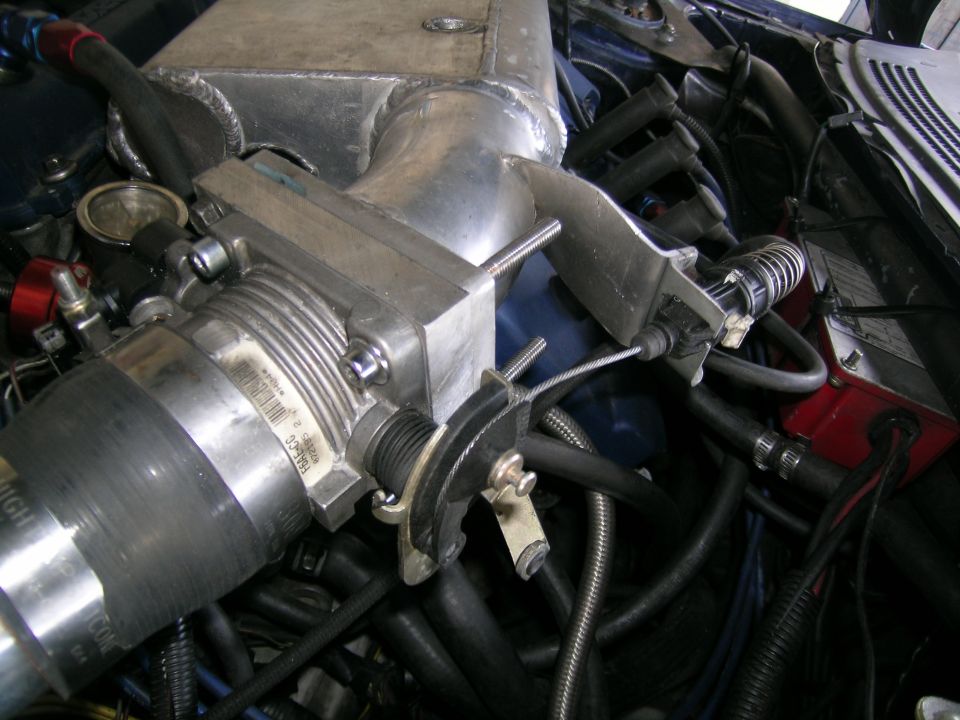 Close-up of a car's engine showing the throttle body, intake manifold, and various hoses and wires