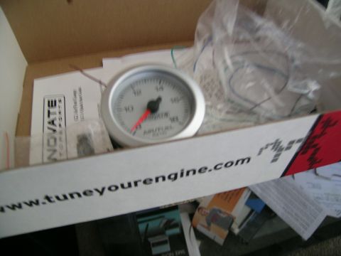 1995 Ford Probe - An air/fuel ratio gauge is shown inside its packaging, alongside various documents and wiring.