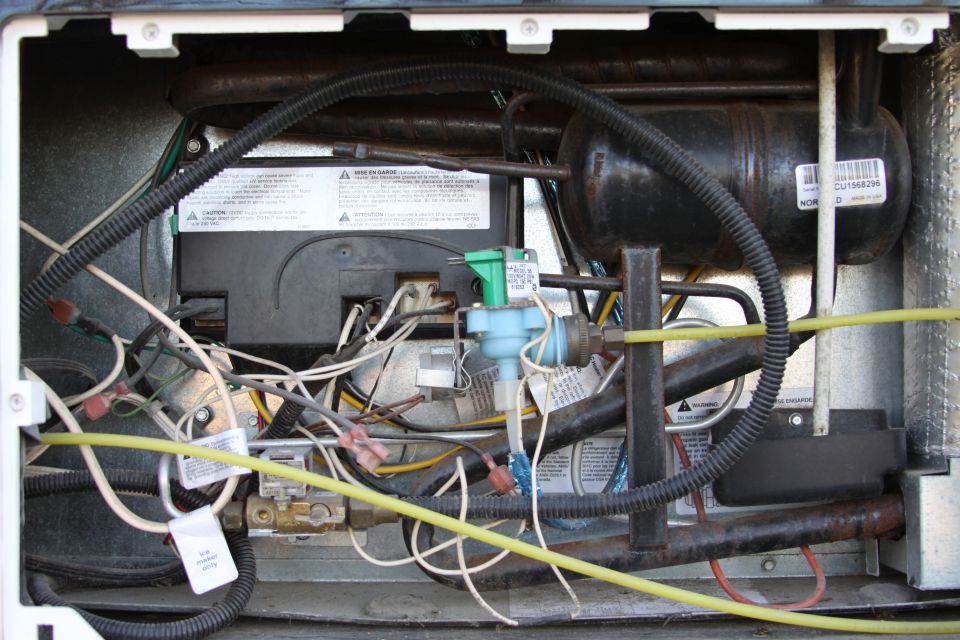 Close-up of refrigerator components with wires and pipes