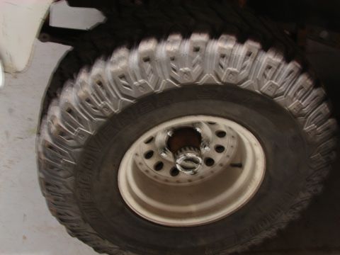 1971 International School Bus - A close-up view of a large off-road tire and wheel, the Supermotors logo at the bottom right.