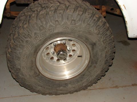 1971 International School Bus - Close-up of a Cooper Discoverer STT tire on a silver alloy wheel with a chrome hub.