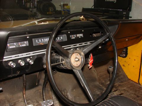 1971 International School Bus - The interior of a yellow vehicle shows the dashboard with gauges, steering wheel, and floor pedals.
