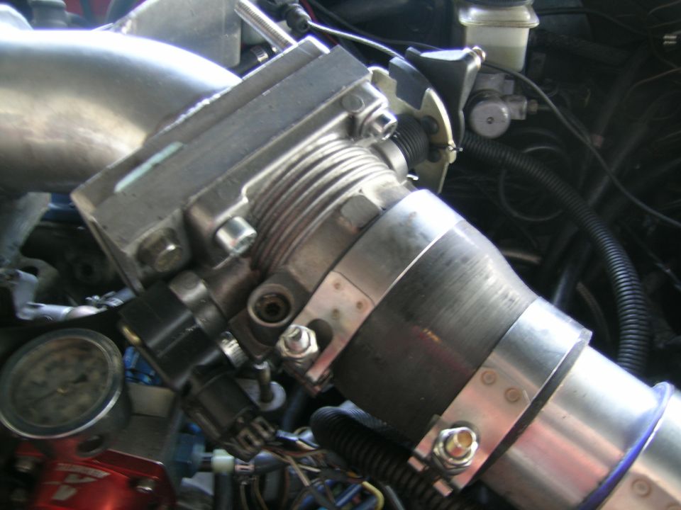 Close-up of engine throttle body and intake piping with a gauge visible