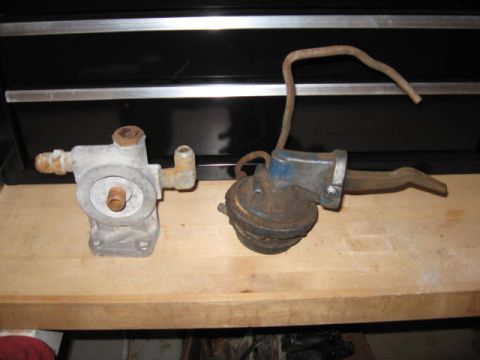 1963 Ford Galaxie - Two automotive parts, a fuel pump and an oil filter housing, are displayed on a wooden workbench.