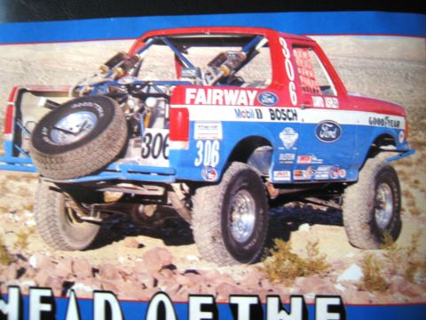 1986 Ford Bronco - This modified off-road truck, likely from the 1980s, displays sponsor decals and a roll cage.